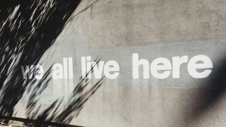 Schrift an der Wand mit der Aufschrift "Wir leben hier alle"