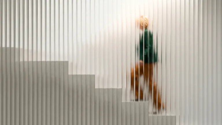 Frau steigt hinter Glaswand Treppe hoch