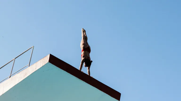 Ein Schwimmer steht auf den Händen auf dem Sprungbrett