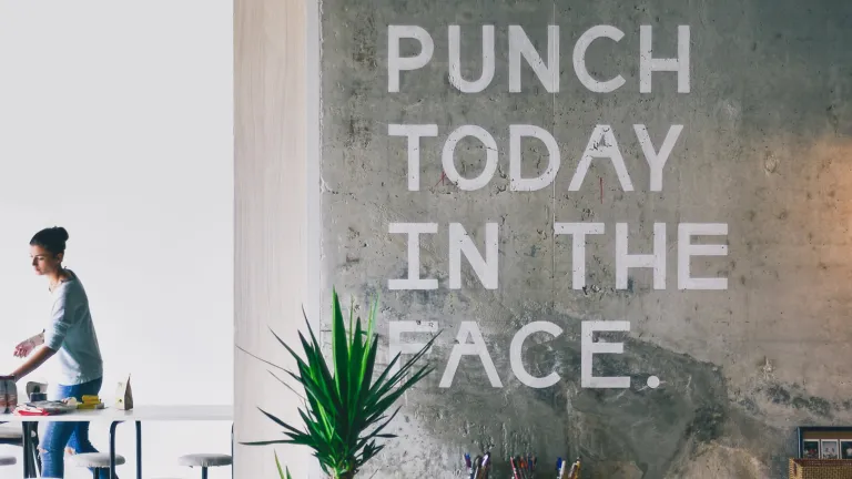 Büro mit der Aufschrift an der Wand ‚Schlag dem heutigen Tag ins Gesicht