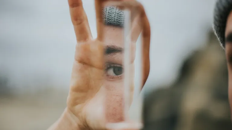 Woman holding piece of mirror reflecting her eye