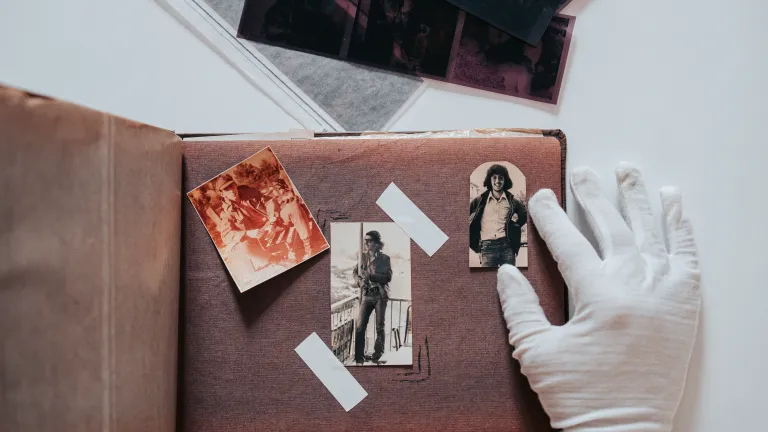 Gloved white hand glueing photos in album