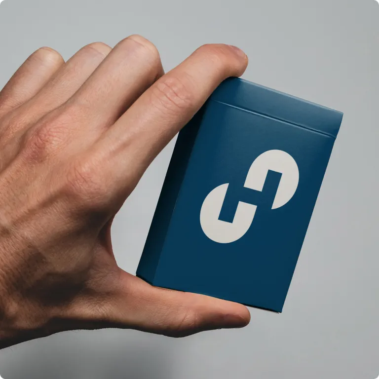 Nahaufnahme einer Hand, die eine kleine, dunkelblaue, rechteckige Box hält. Auf der Vorderseite der Verpackung ist mittig ein großes, weißes Holcim-Logo platziert.