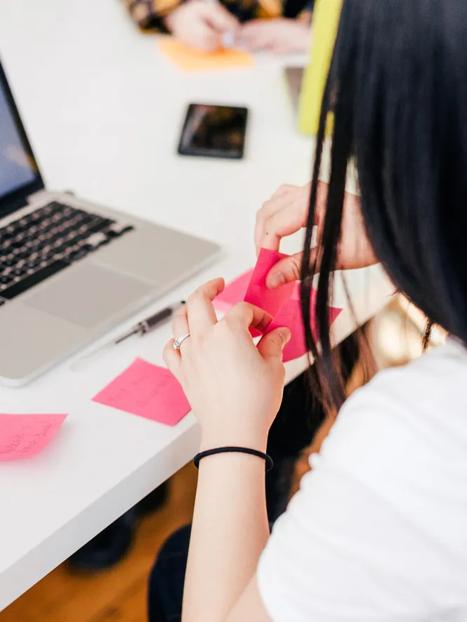 woman using pink post-its in front of laptop