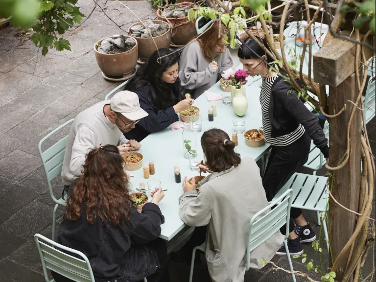 Vogelperspektive von Arbeitskollegen, die sich um einen Tisch in einem Innenhof versammelt haben.