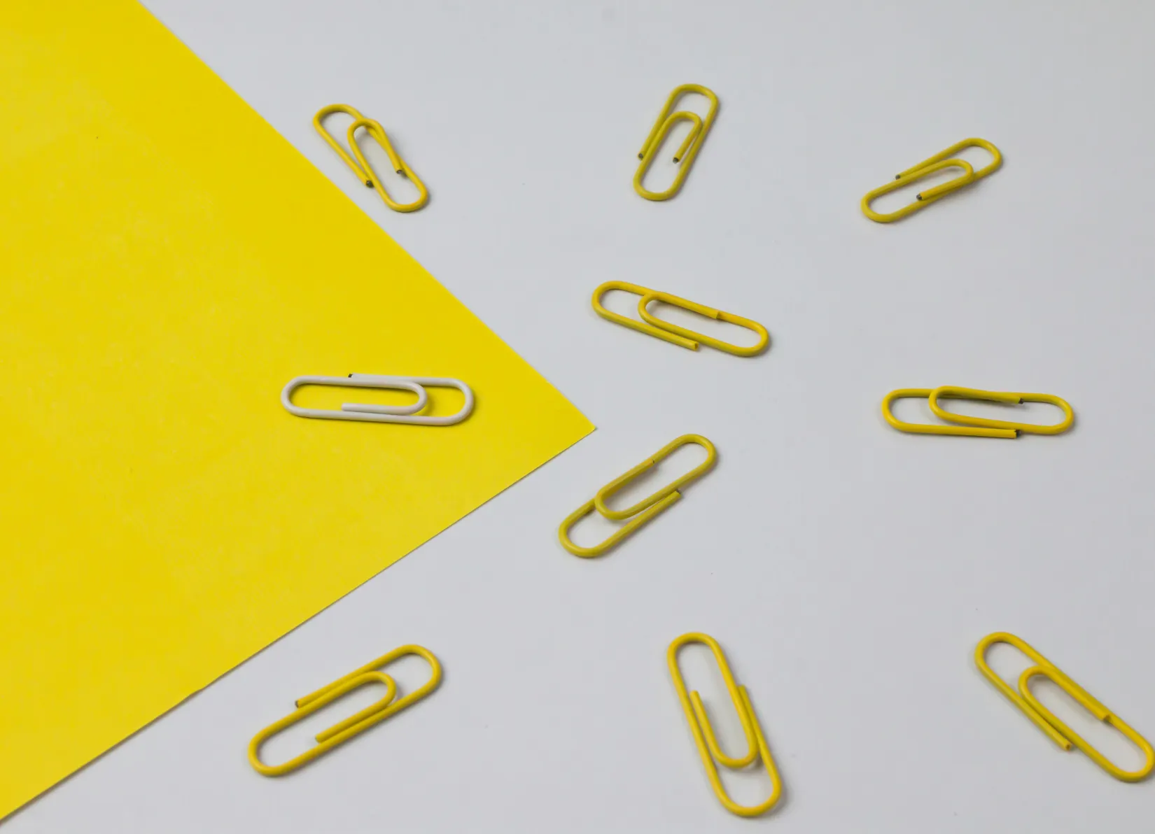 Paperclips on yellow paper and white table