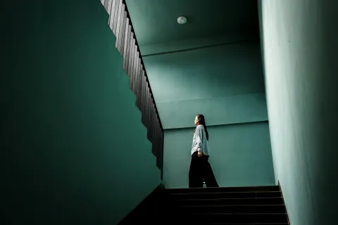 Lady walking up a stairwell with green walls