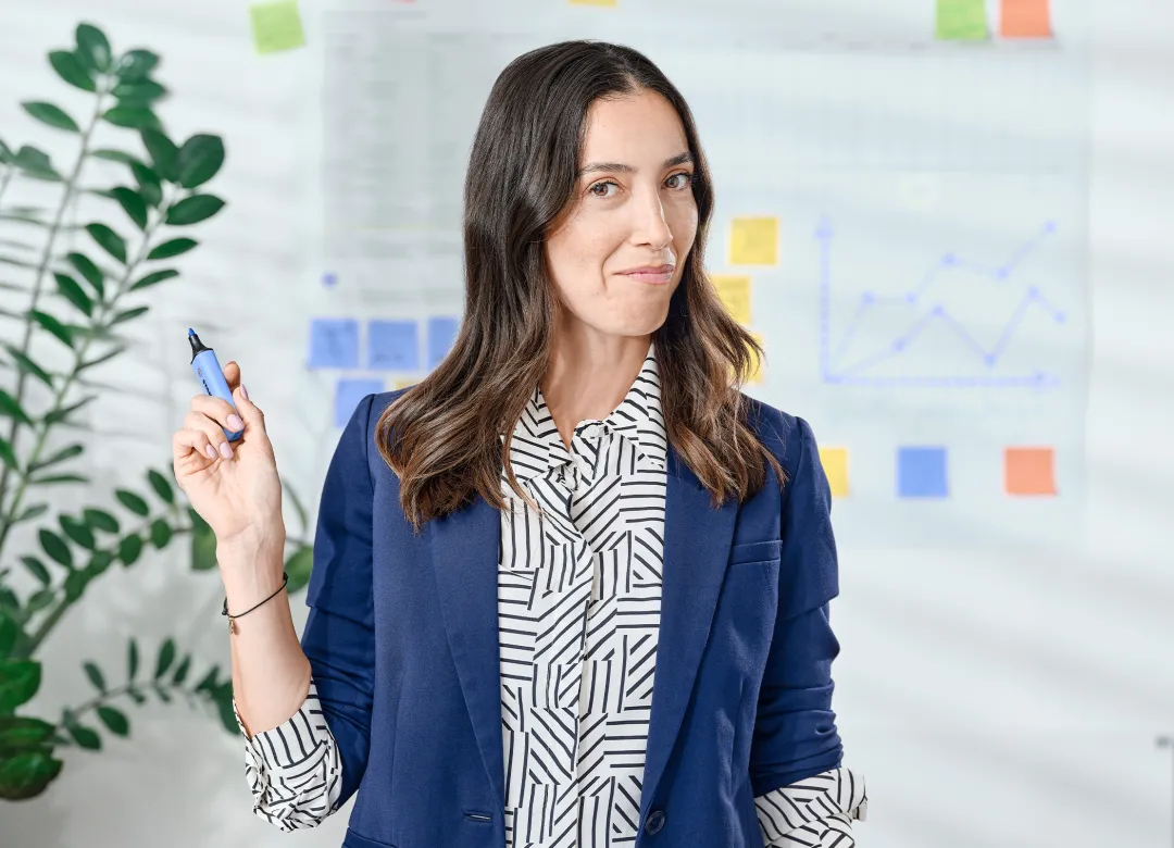 Woman in an office holding up a highlighter and looking mischievous